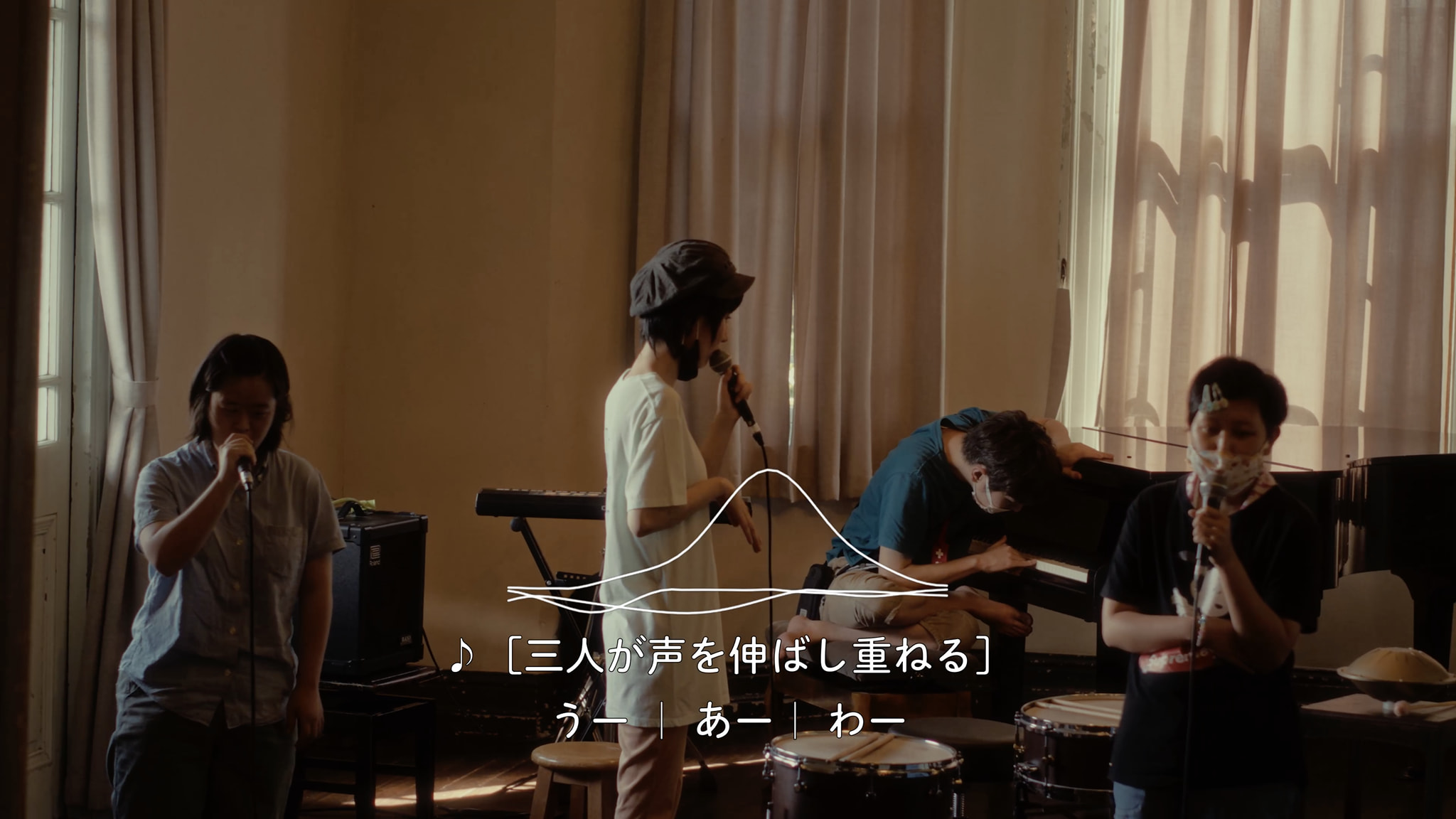 三人がマイクを持ち、部屋で歌っています。キーボードとドラムが見えます。「三人が声を伸ばし重ねる」と表示されています。